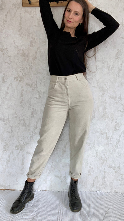 A retro woman in a black top and Cordhose retro 1990 pants made in Italy posing against a wall.
