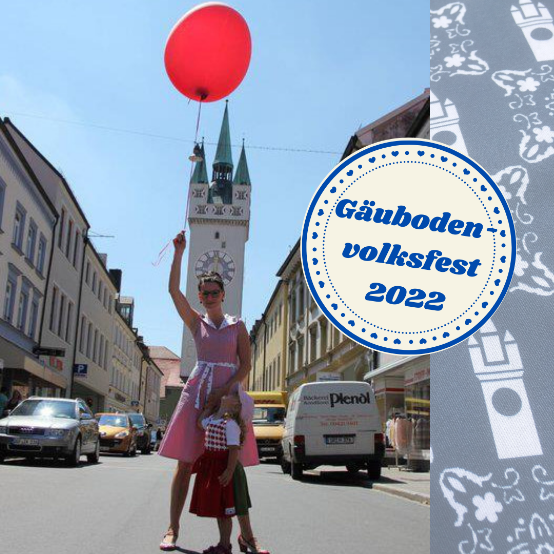 Vor dem Straubinger Stadtturm steht eine Frau und ein kleines Mädchen mit Luftballon in der Hand.