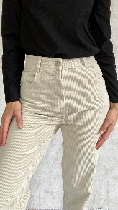 A woman wearing beige Cordhose retro 1990 corduroy pants made in Italy and a black top.
