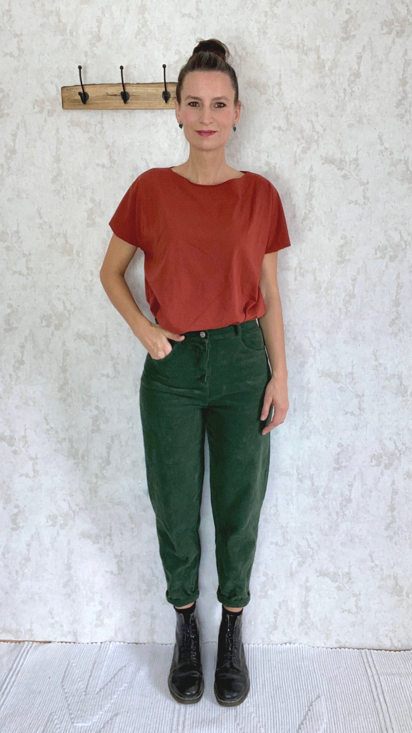 A woman wearing a retro red t-shirt and a pair of green Baumwolle cordhose retro 1990 pants made in Italy.