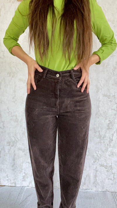 A woman wearing Cordhose retro 1990 pants made in Italy Baumwolle fabric and a green shirt.