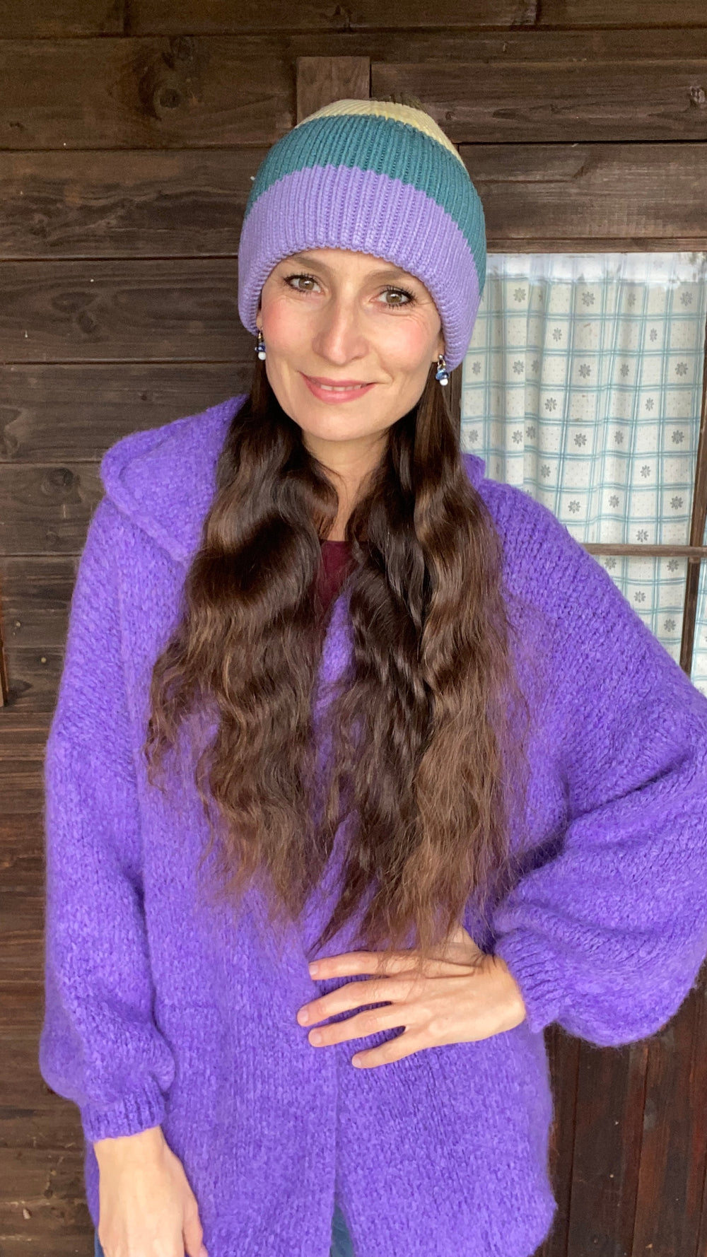 Strickjacke mit Kapuze in lila mit Mütze. 